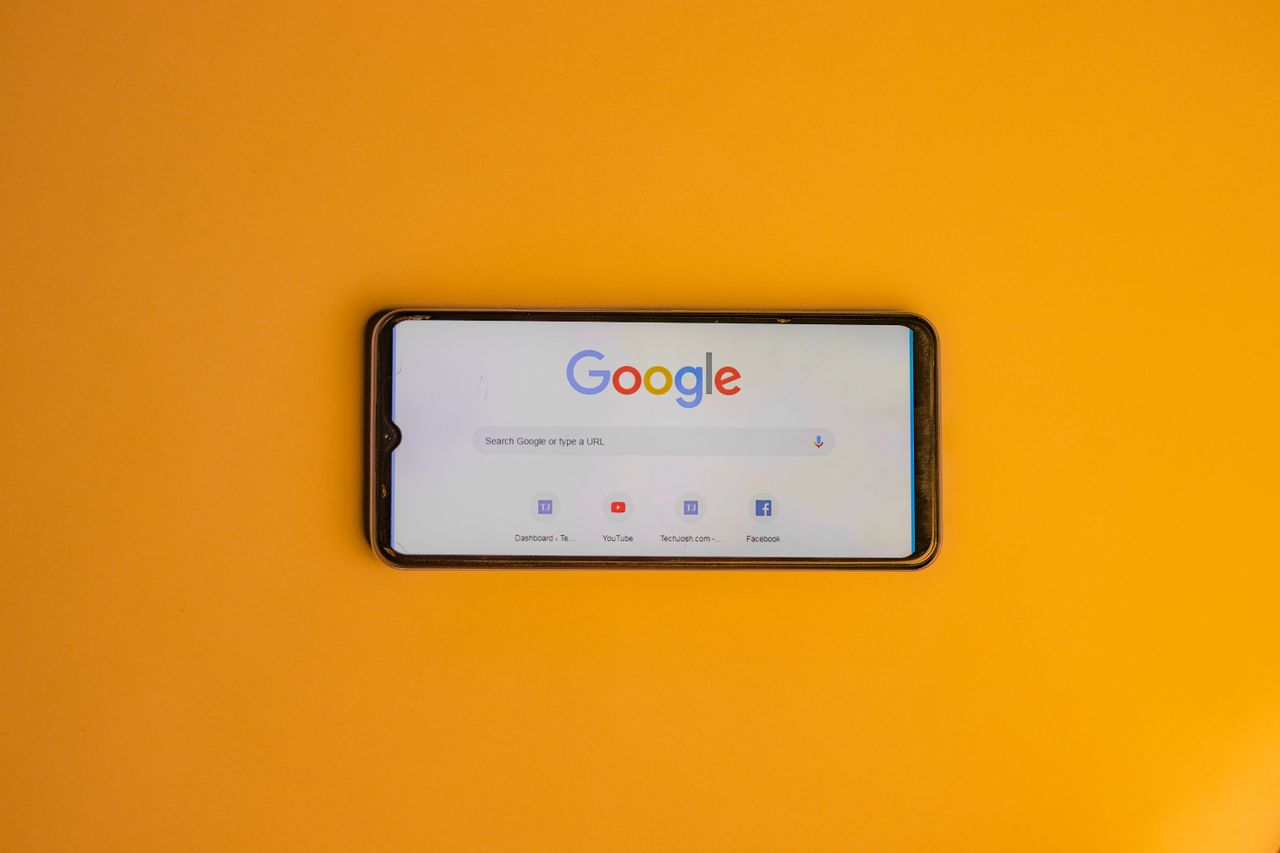creative-02 Smartphone displaying Google search page on a vibrant yellow background.