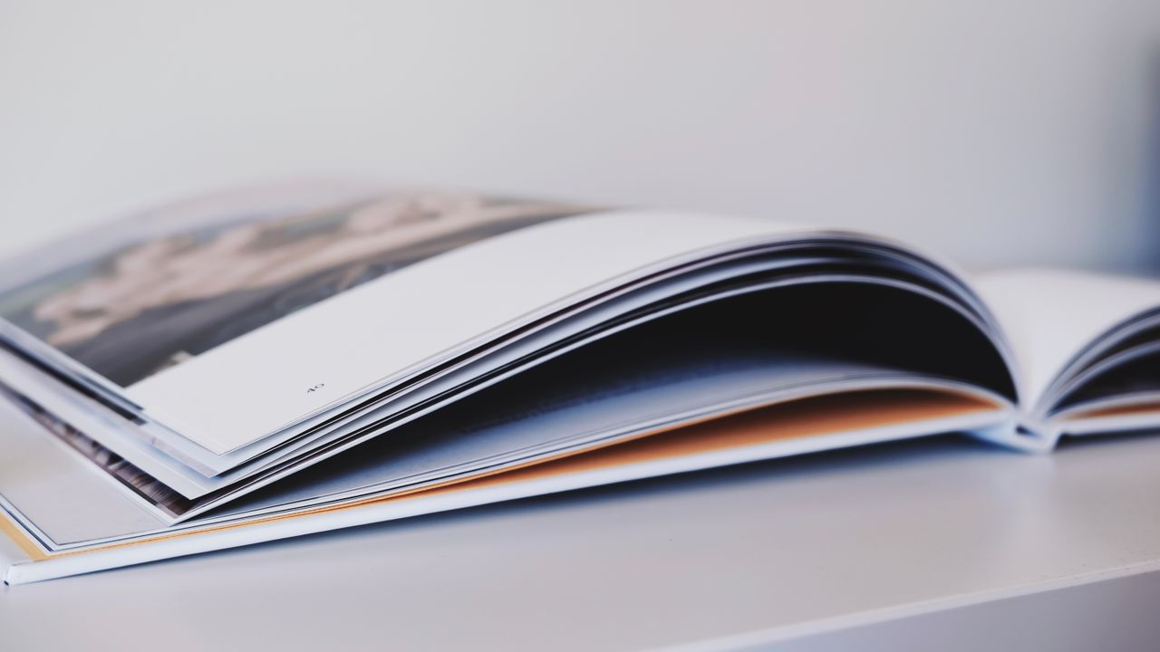 Services-02 Close-up of an open magazine lying on a white surface, showcasing glossy pages.